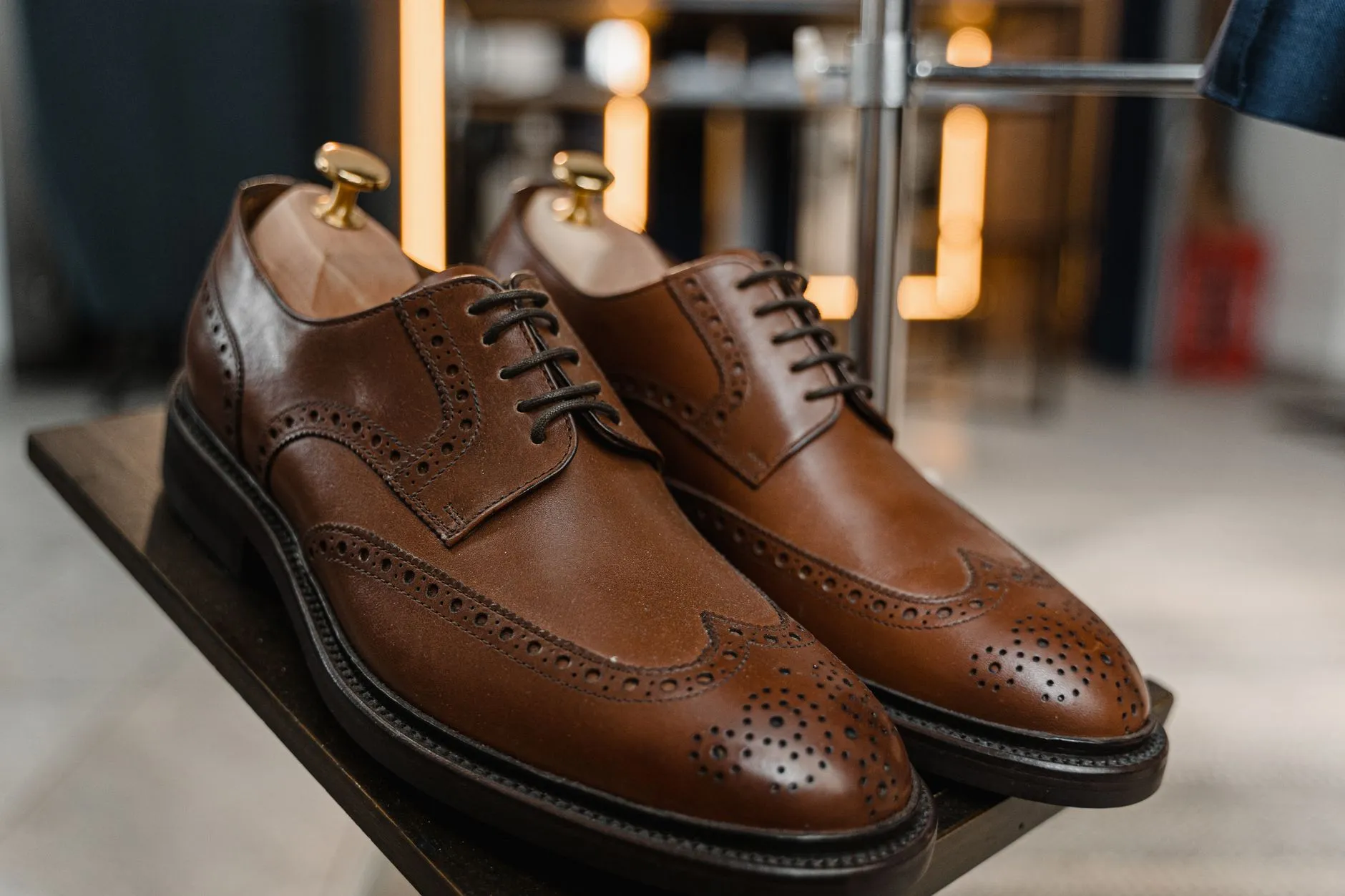 Lederschuhe mit Pflegezubehör: Schuhcreme, Bürste und Zedernholzspanner auf einem Holztisch