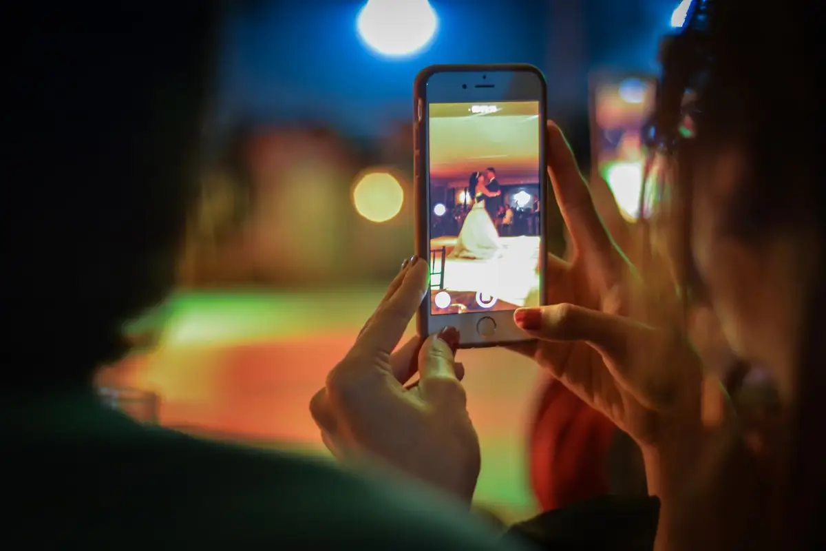 Hände halten ein Smartphone und filmen ein tanzendes Paar